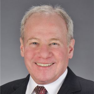 A portrait of a smiling man wearing a suit