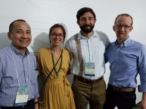 Three men and one woman standing and smiling next to each other