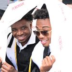 two man graduates taking shelter from rain in Fordham printed tarp